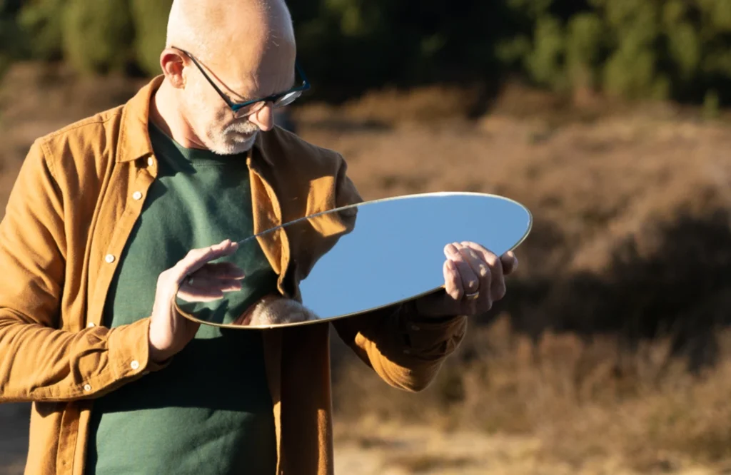 Mens kijkt in spiegel, symbool voor bewustwording en zelfreflectie – zo binnen, zo buiten
